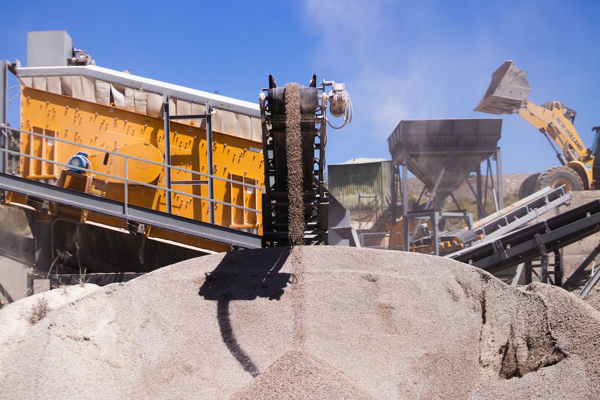 Macchinari per cava che scaricano ghiaia su un cumulo.